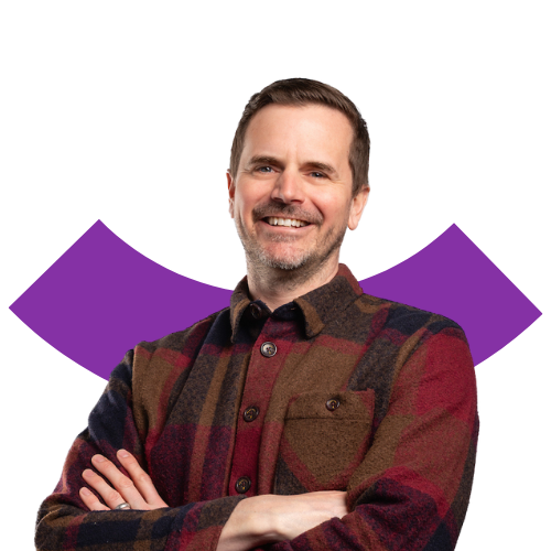 A portrait of a smiling, middle aged white man with short hair and beard